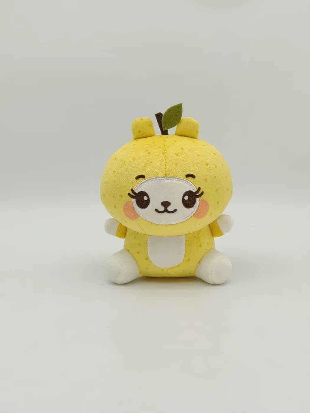 Yellow bear plush toy in a lemon hood with blushed cheeks