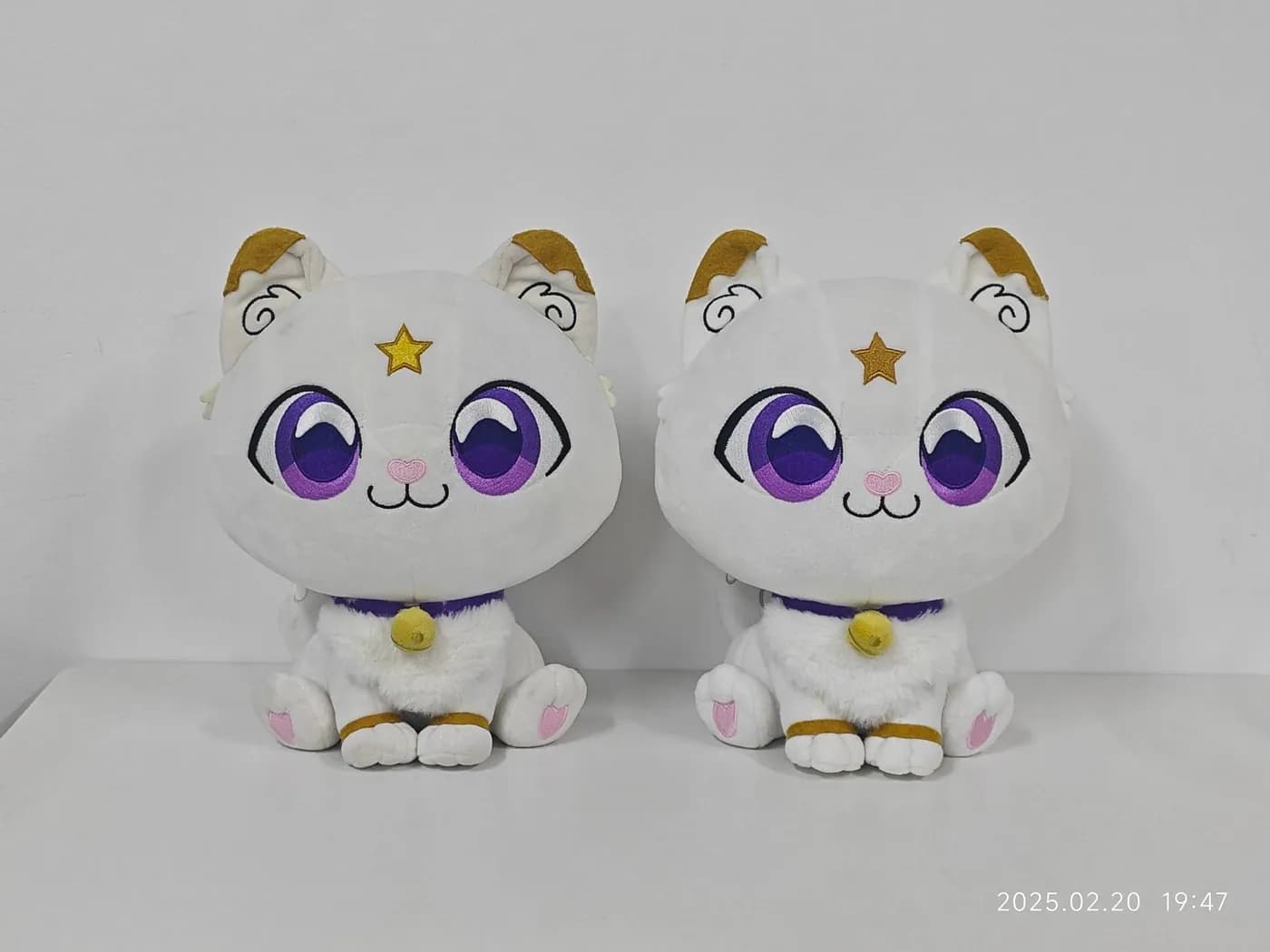 Pair of white cat plush toys with printed violet eyes and gilt ears