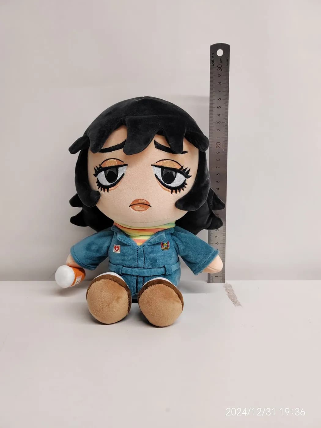 Cotton doll with dark wefted hair and a denim outfit, shown with a steel rule